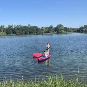 zwei Kinder mit pinken Luftmatratzen aufm See