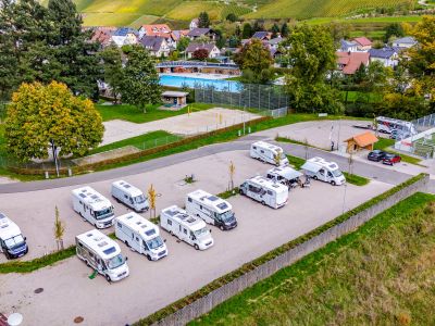 Drohnenbild vom Wohnmobilstellplatz Kappelrodeck, zu sehen Camper, im Hintergrund das Schwimmbad, Häuser und Weinberge