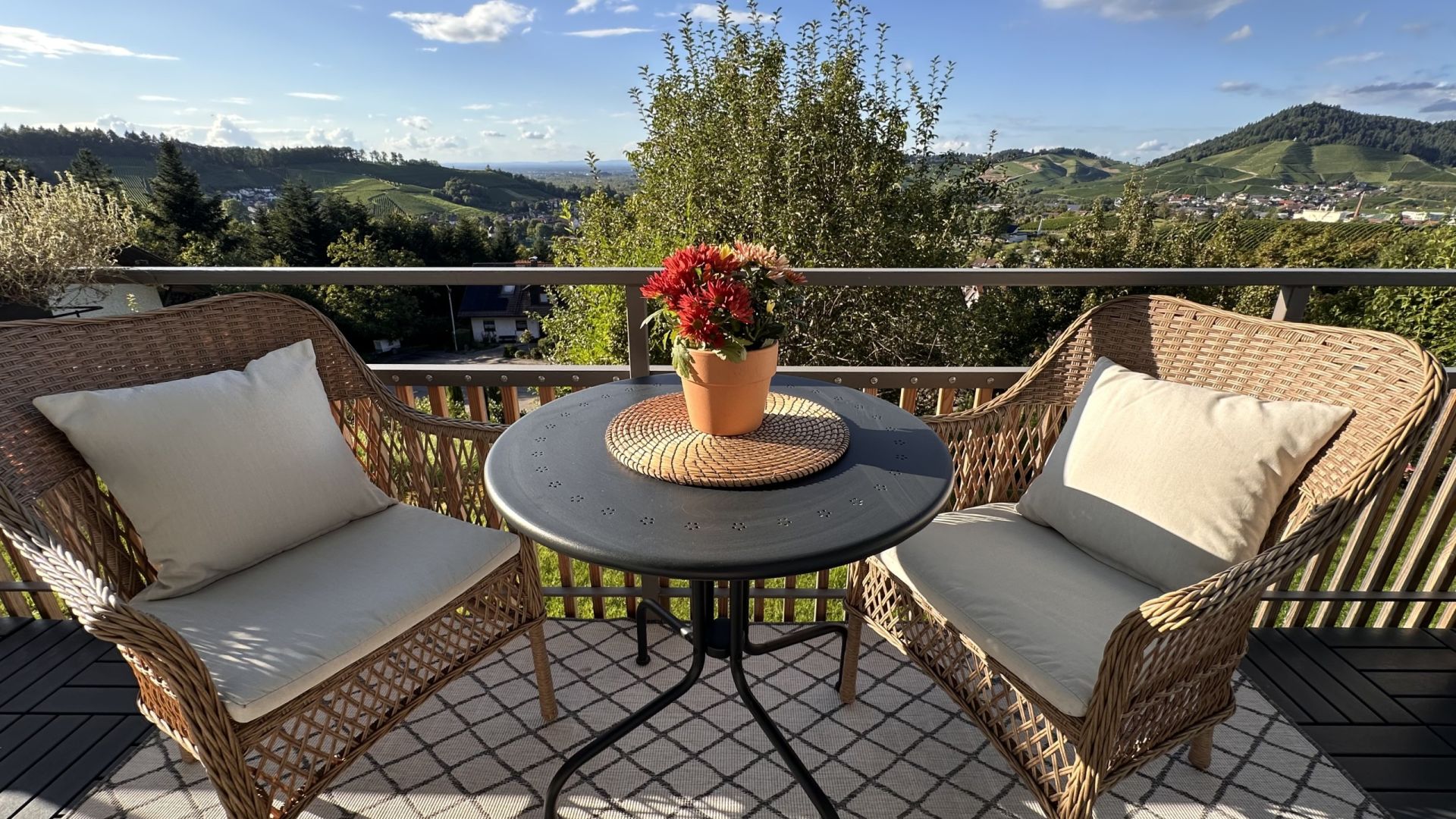 Balkon mit zwei Stühlen und einem Tisch mit Blumentopf und Blick ins Grüne
